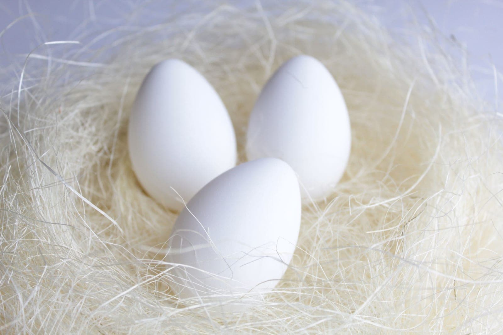 Brown eggs resting in a straw-lined nest